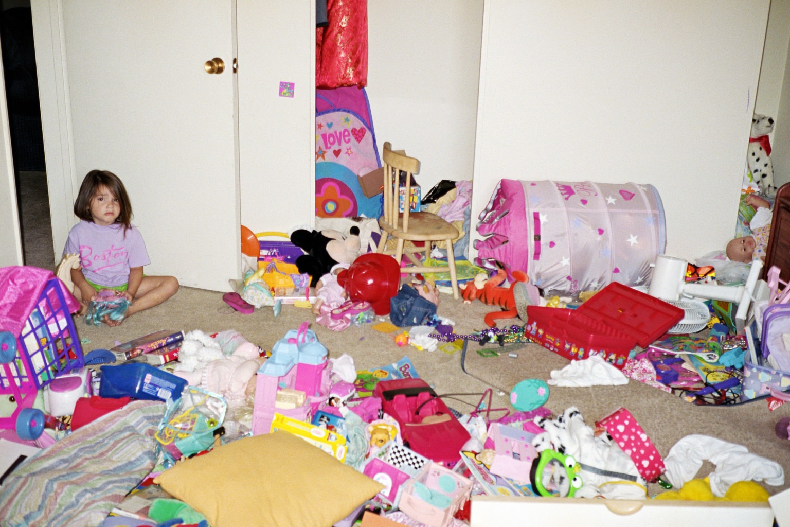 Girl (4-6) sitting on floor in messy room