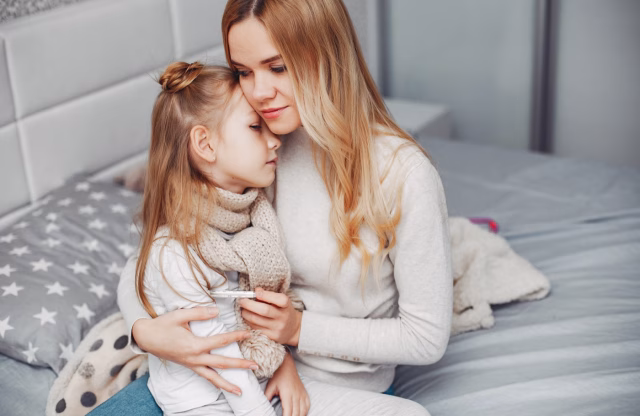 Mama objema prehlajeno deklico v domači spalnici